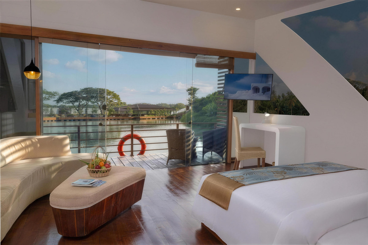 Water Cabana interior: curved sofa, timber floor and glass doors opening onto a deck over the lake