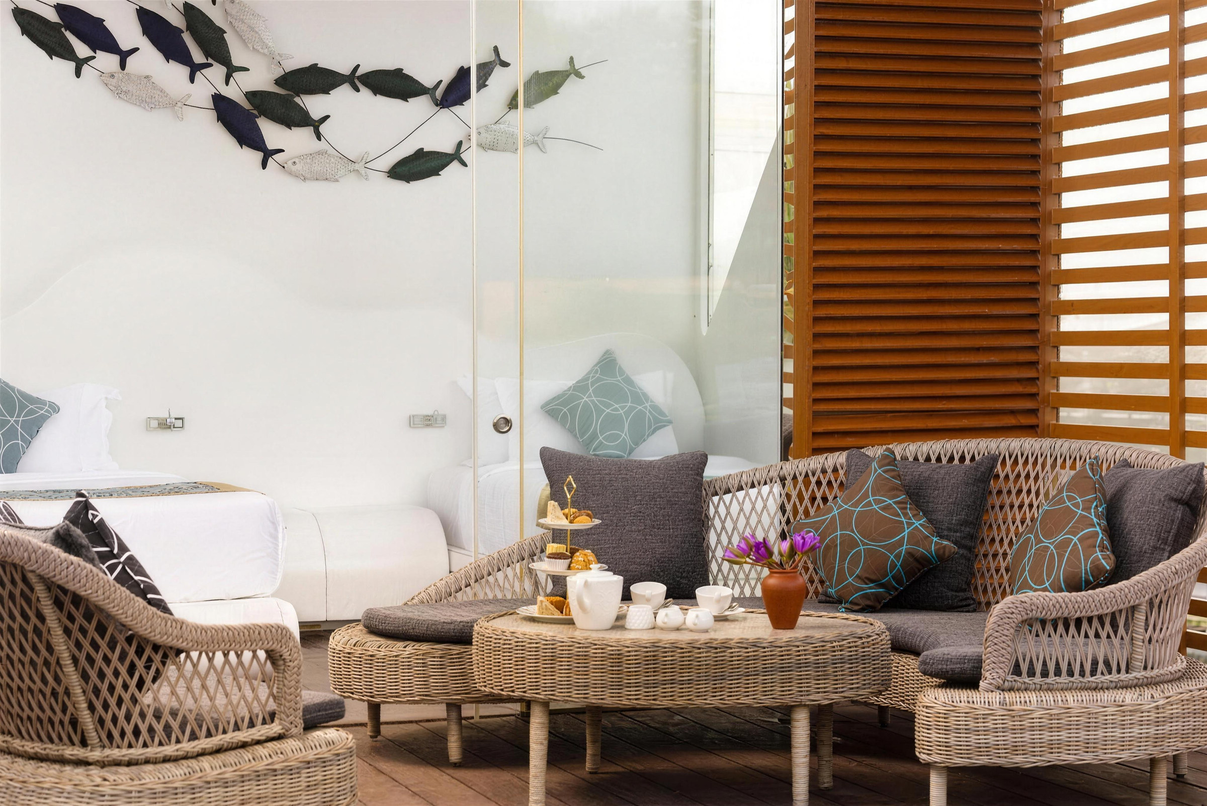 The deck of a Premium Water Cabana over the lake with rattan sofas and high tea