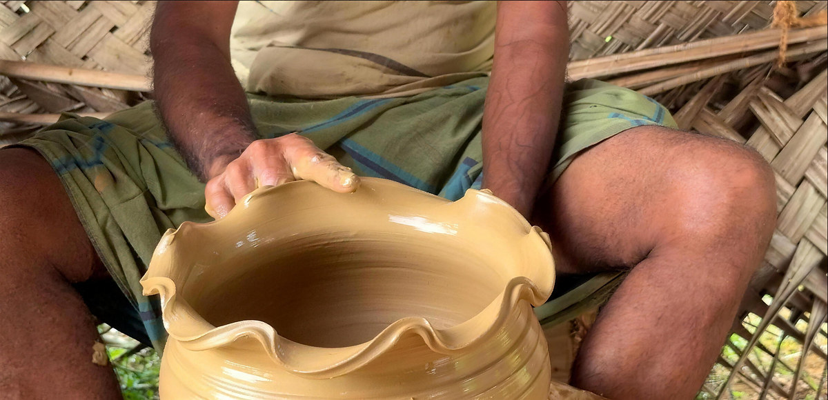 Hands shaping a clay pot