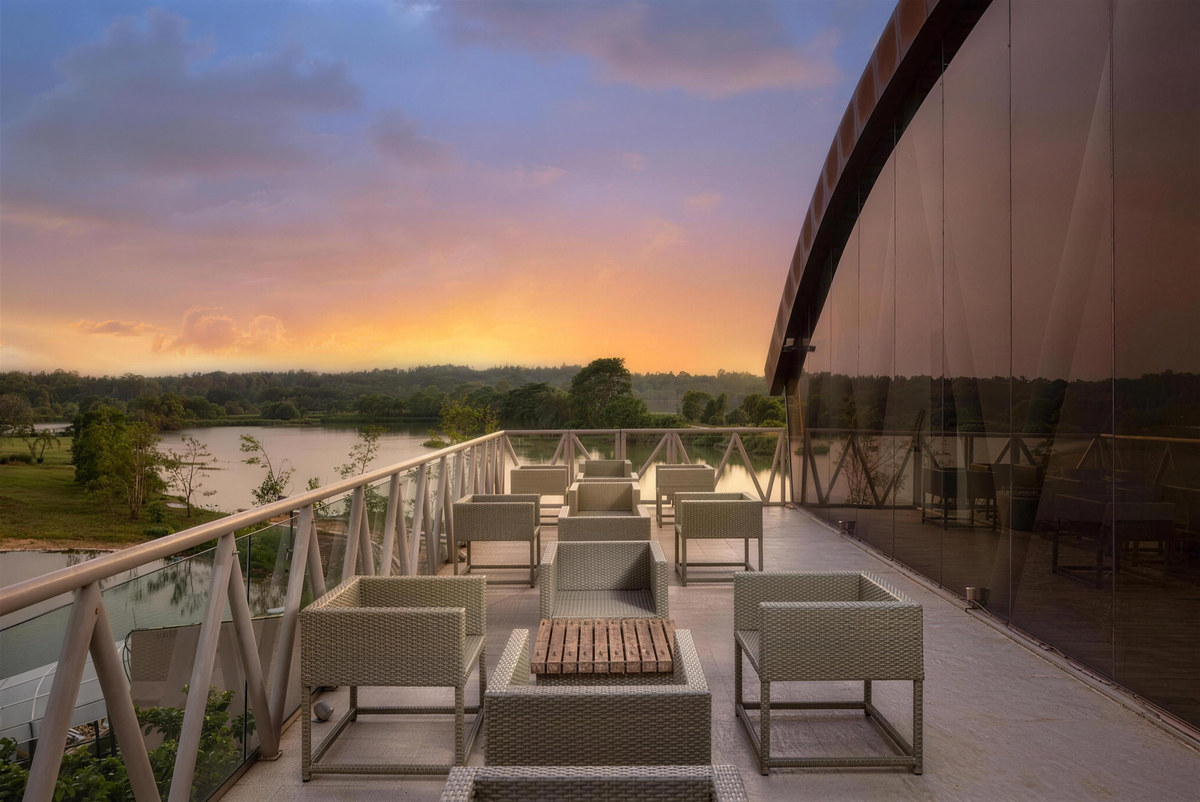 A rooftop terrace with lounge seating looking over the lake at sunset