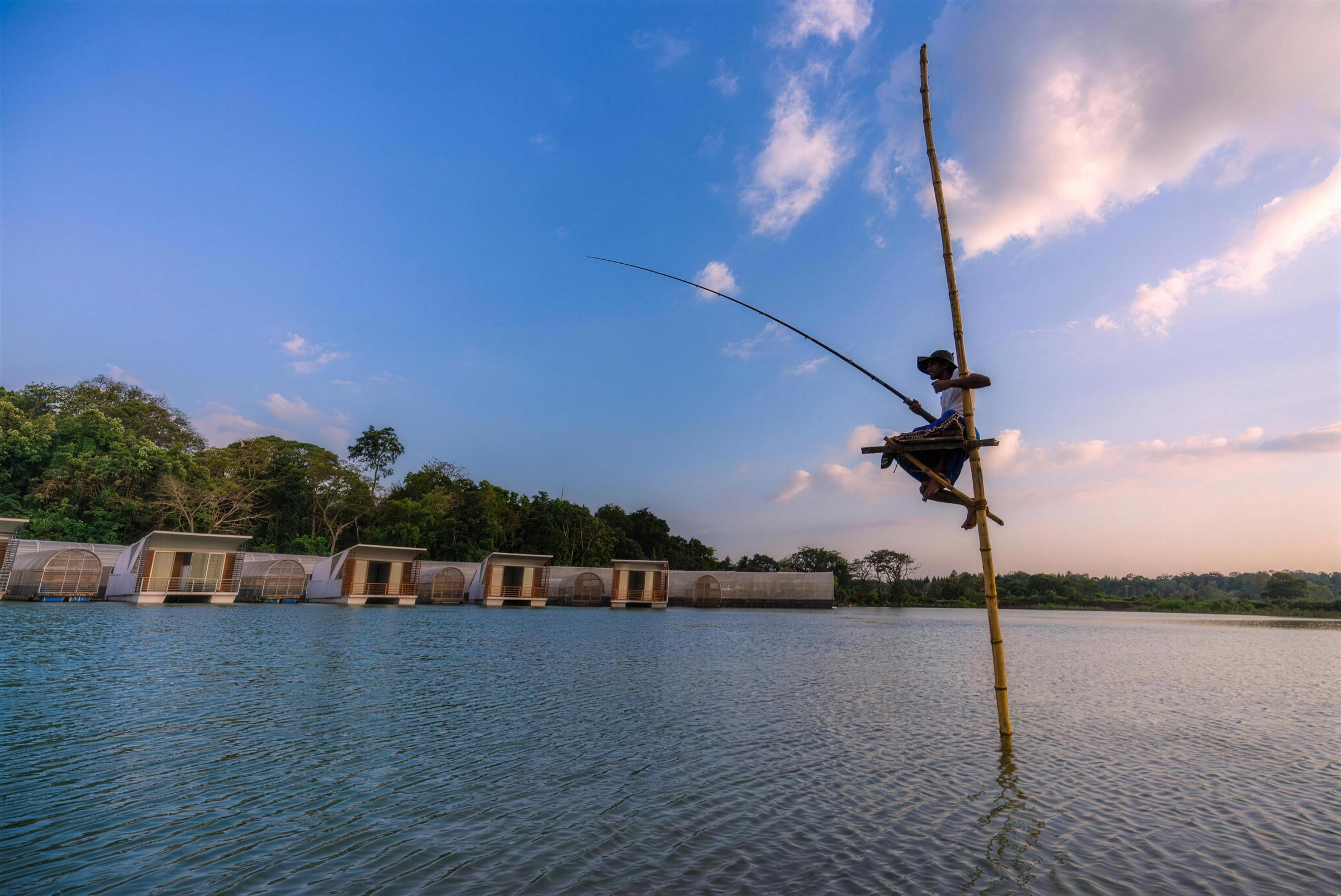 A stilt fisherman above the lake in front of the cabanas