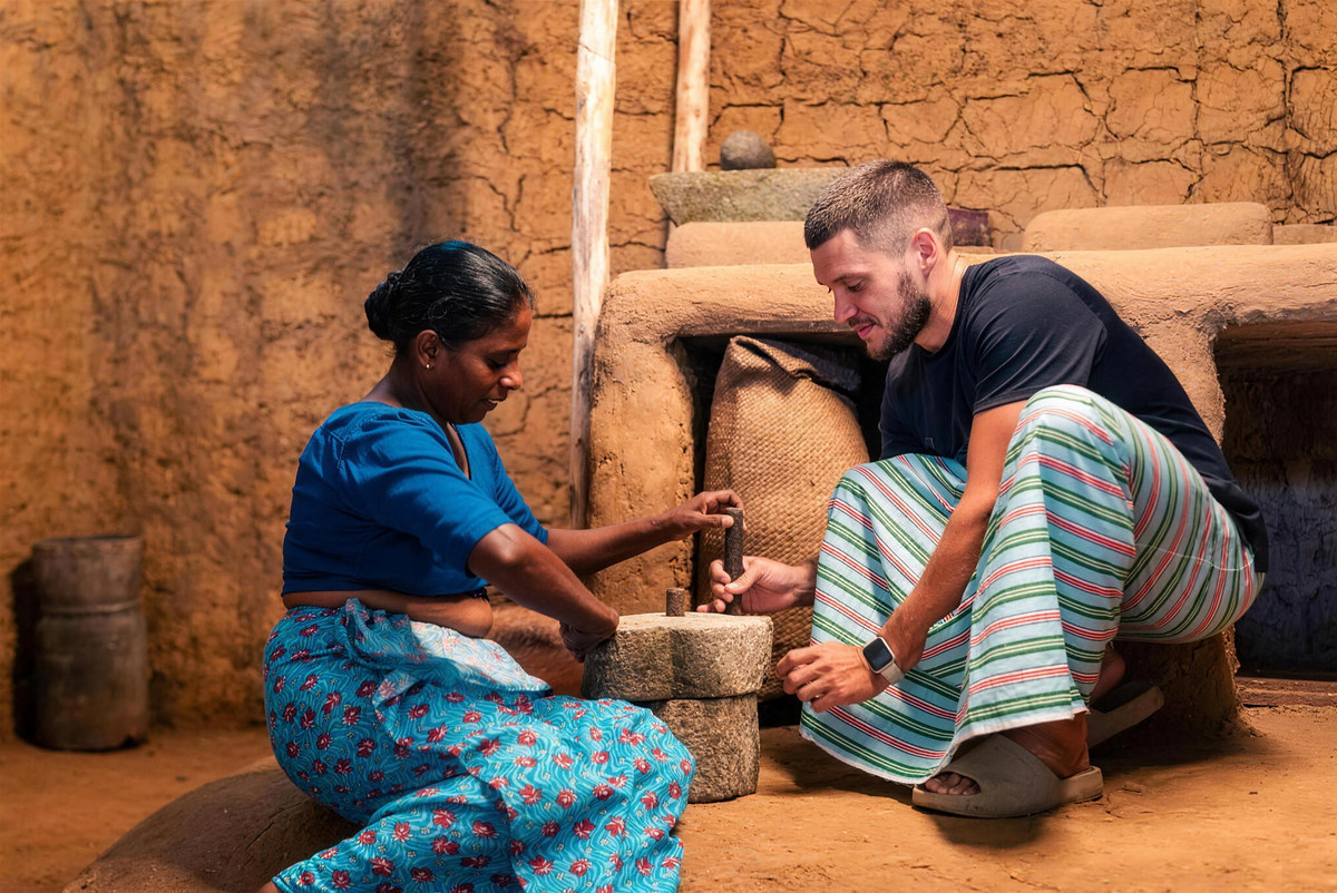 A village cook shows a guest how to grind spices on a stone