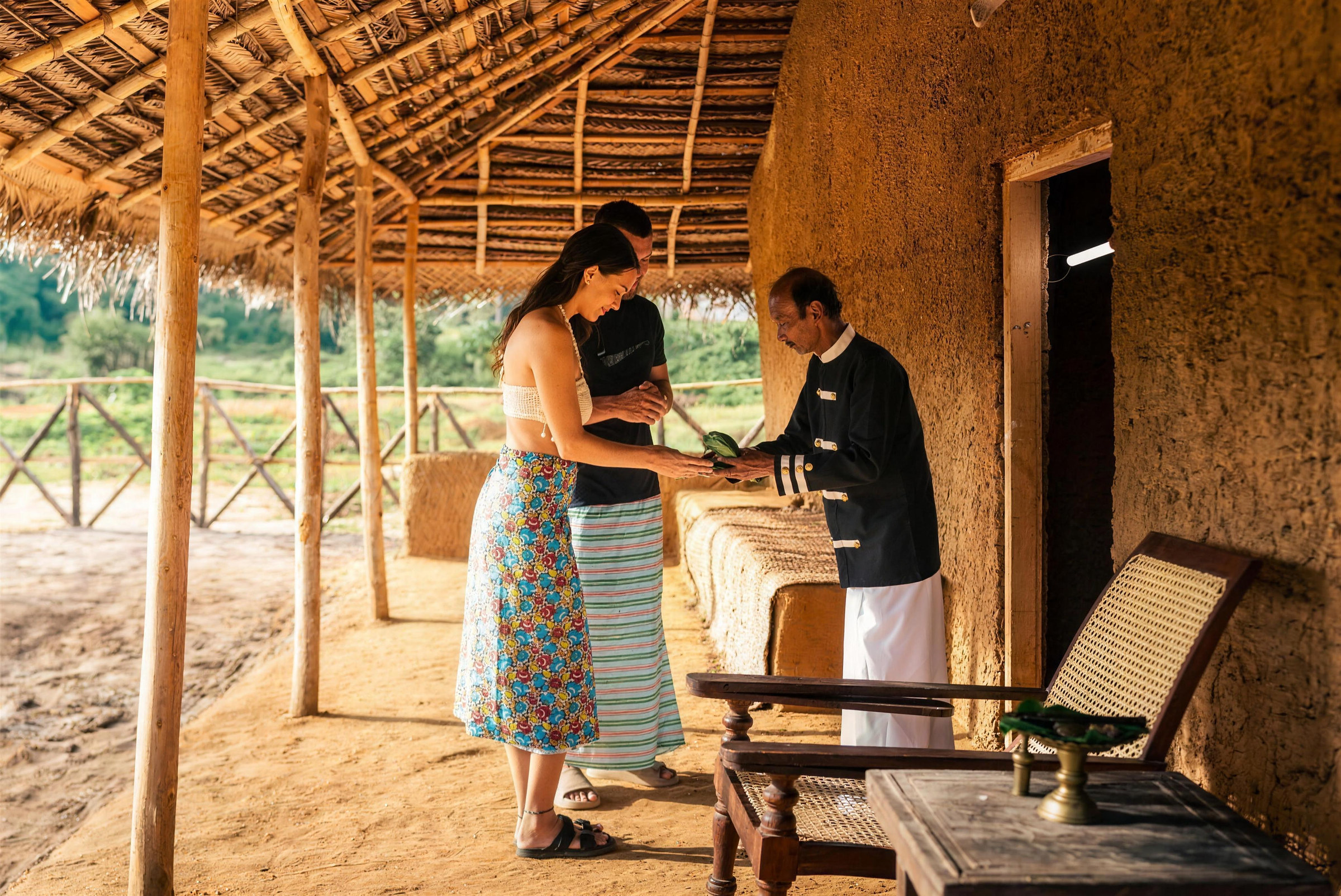 A host welcomes guests with betel leaves on the veranda of the village house